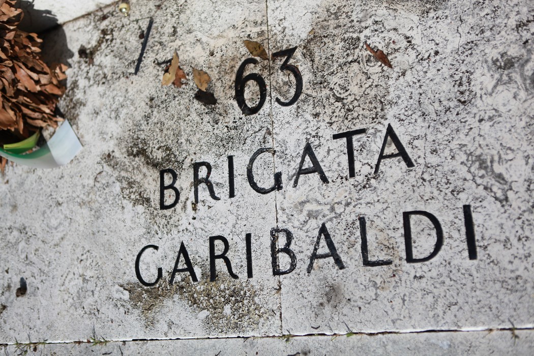 Monumento commemorativo in onore della 63° Brigata Garibaldi, con dettagli in pietra e foglie secche.