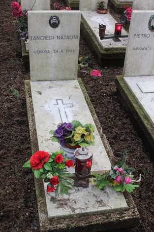 Tombe commemorative con fiori e lumini, dedicate ai caduti per la Libertà. Atmosfera di rispetto e memoriale.