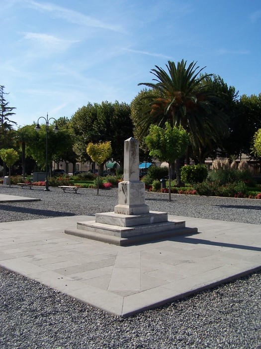 Cippo di Vada, un monumento immerso nel verde, circondato da piante e un bel cielo azzurro.