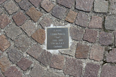 Pietra d'inciampo dedicata a Antonio Pezzotta, partigiano, incastonata nel pavimento.