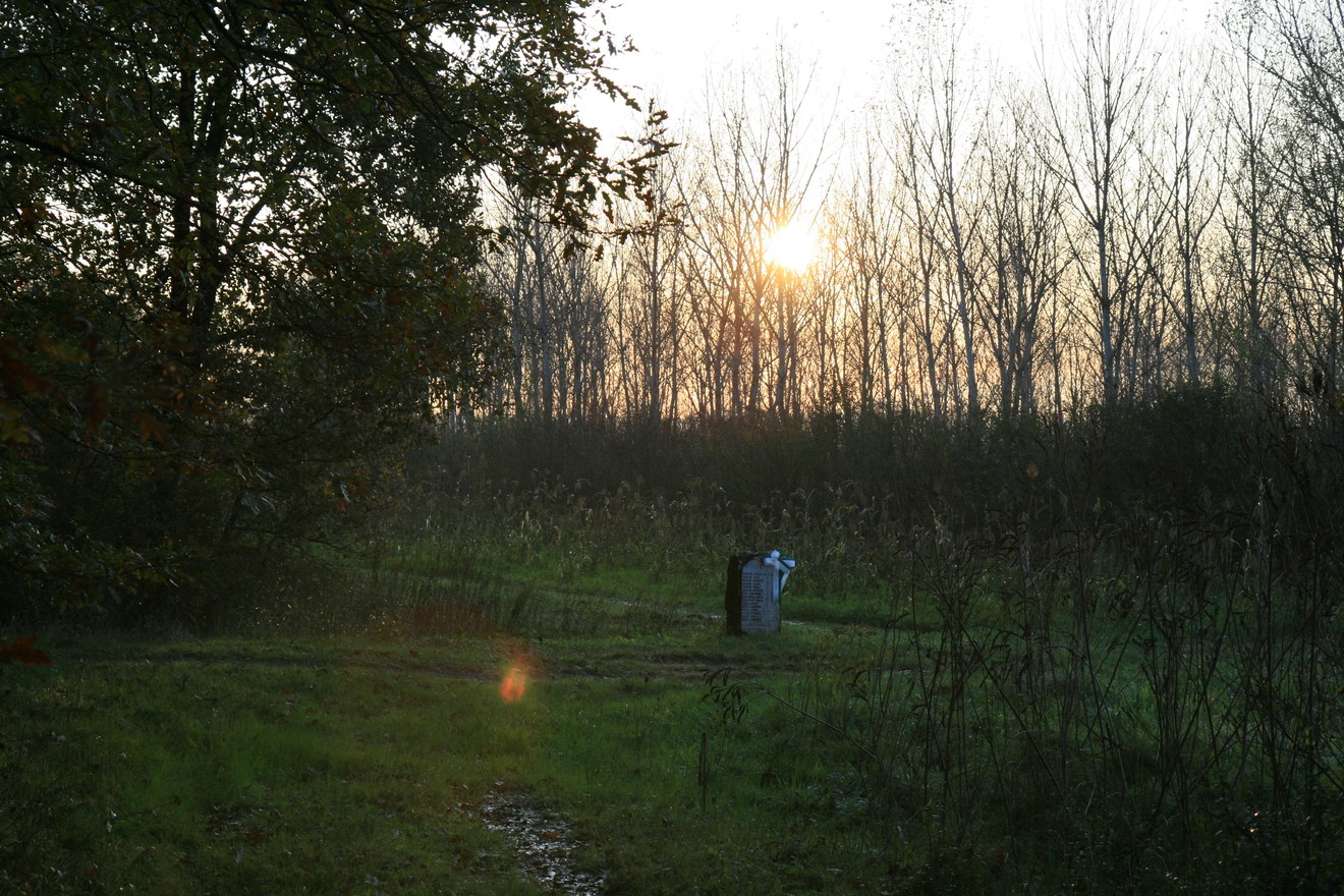 Cippo commemorativo immerso nella natura al tramonto, dedicato alle famiglie Brinati e Natali.