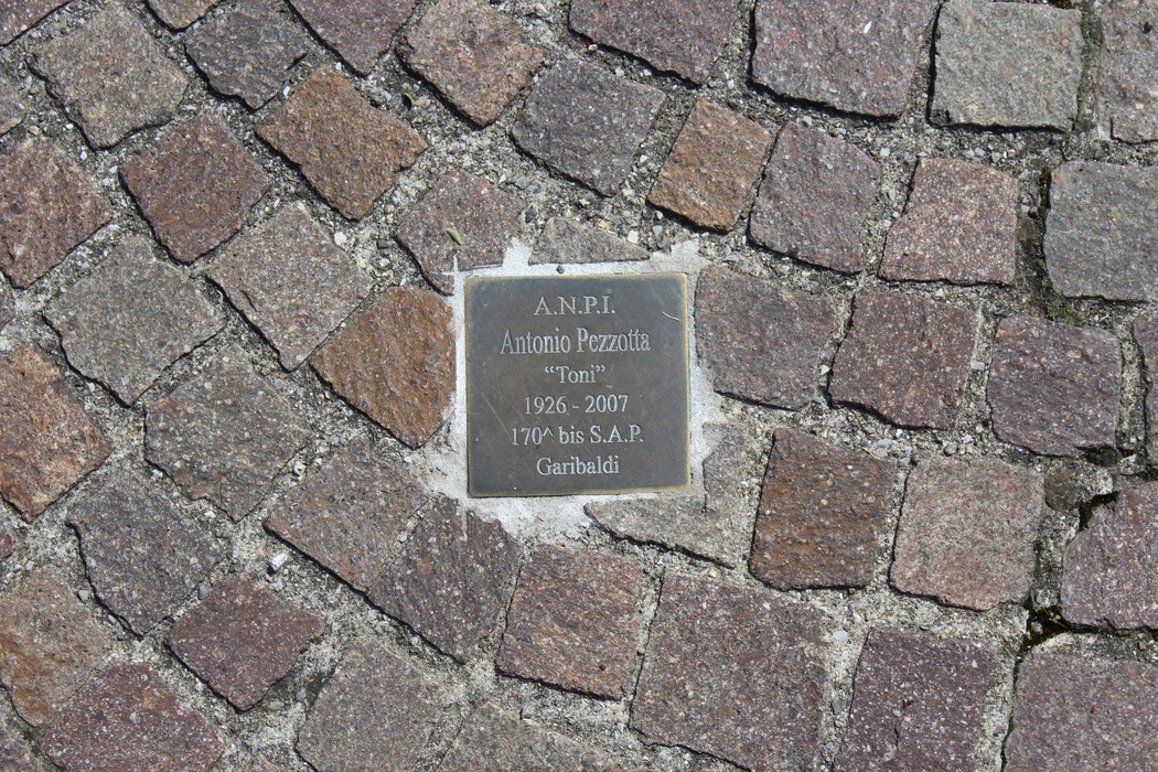 Pietra d'inciampo dedicata a Antonio Pezzotta, partigiano, incastonata nel pavimento.