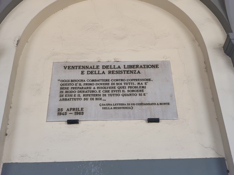 Lapide in marmo con iscrizione, fissata alla parete sotto un arco d'ingresso.