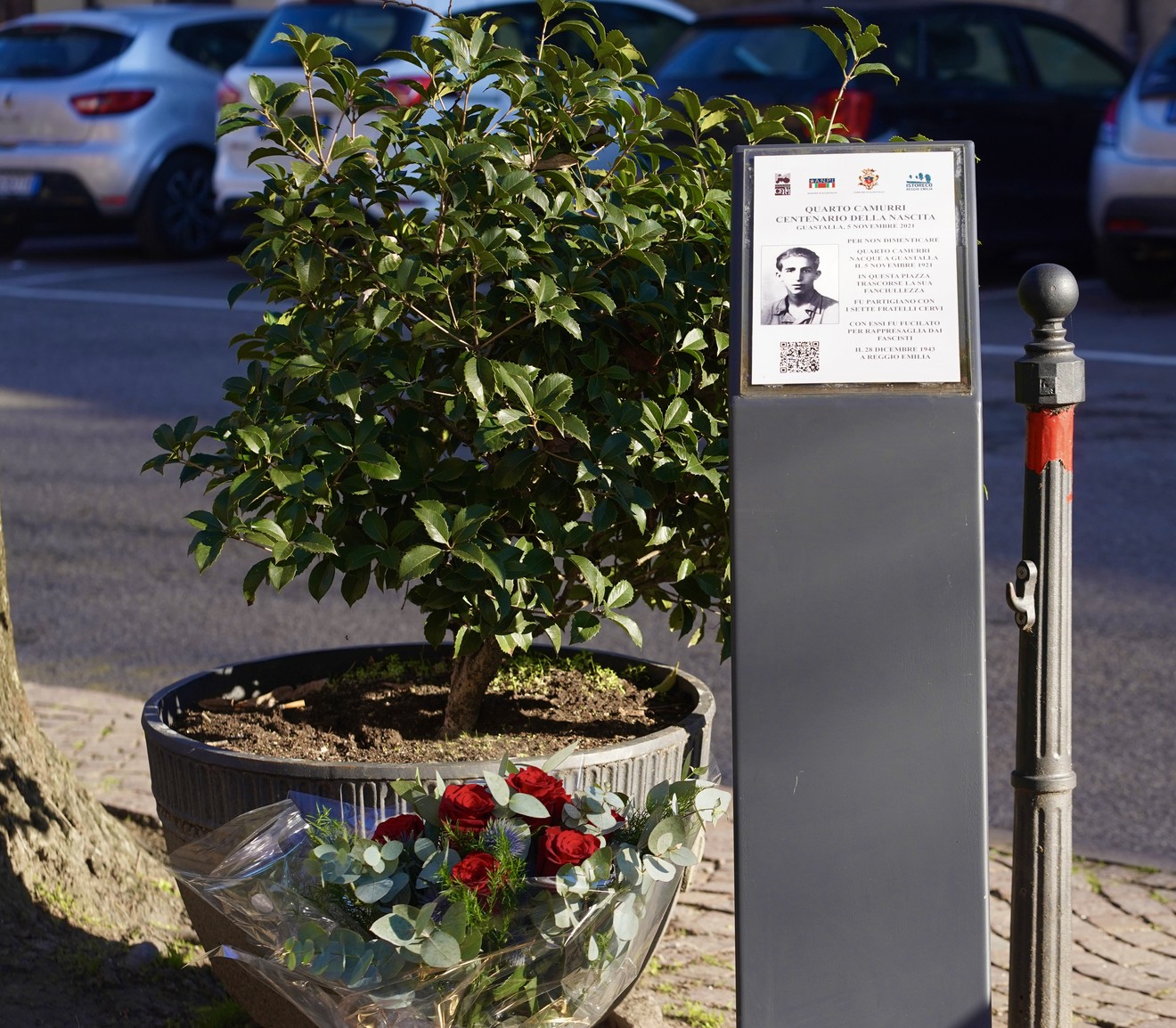 Stele commemorativa a Camurri con fiori, in ricordo di una figura significativa della storia locale.