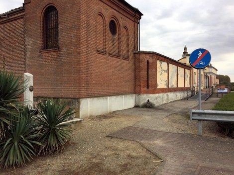 Cippo a Genestrone, un monumento storico circondato da edifici e vegetazione.