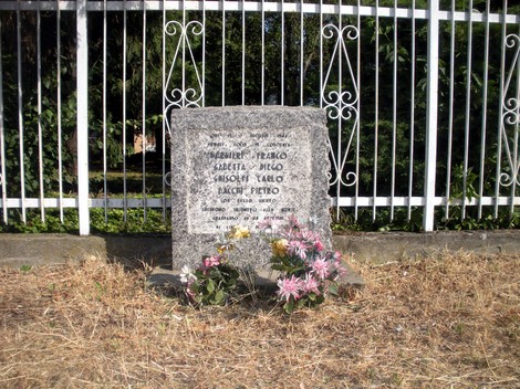 Monumento commemorativo dedicato ai fucilati della via Emilia, con fiori e inscrizioni in memoria delle vittime.