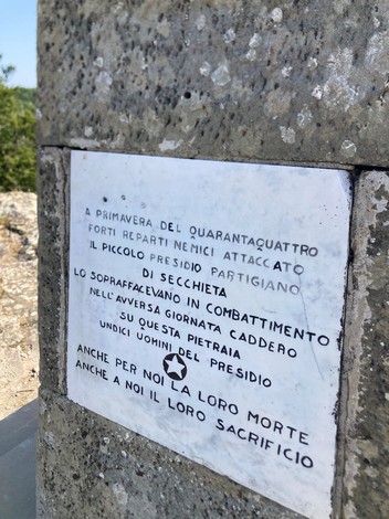 Monumento in Secchieta con iscrizione commemorativa che ricorda la resistenza e il sacrificio dei partigiani.