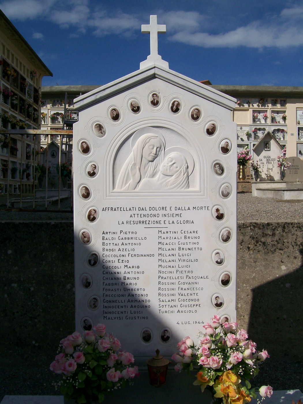 Sepolcro commemorativo delle vittime dell'eccidio di Meleto, con croce e immagini votive.