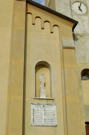 Lapide commemorativa ai caduti di Sassalbo, affiancata da una statua e situata su un edificio storico.