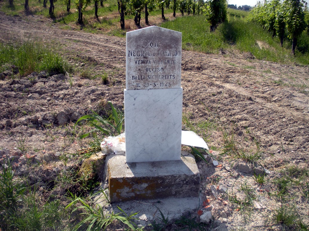 Lapide commemorativa immersa nel verde, dedicata alla memoria di Negri in un contesto naturale.