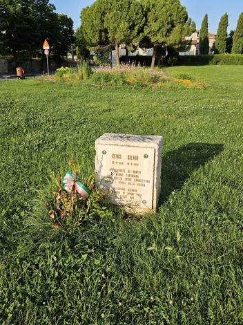 Cippo commemorativo di Cenci, immerso in un prato verde, circondato da alberi e vicinanze tranquille.