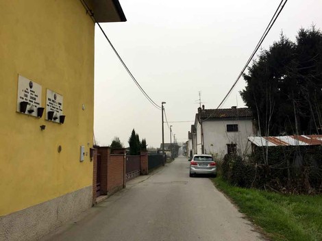 Veduta di una strada con case e lapidi, che rappresentano la località di Orbelli e Savasini.