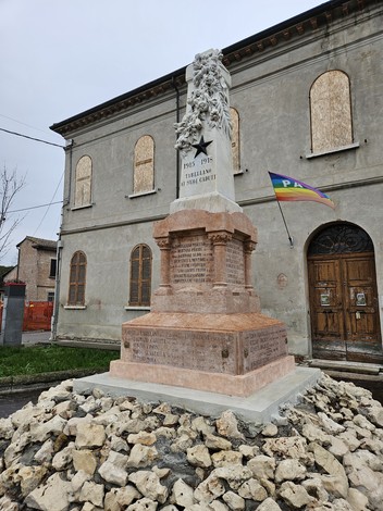 Monumento ai Caduti di Tabellano, con base in granito e statue, circondato da un cumulo di pietre.