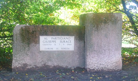 Monumento commemorativo dedicato a Giuseppe Surace, partigiano caduto nel 1944, immerso nella natura.