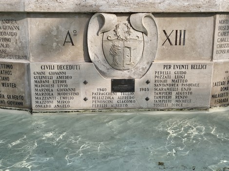 Fontana Monumentale con decorazioni e iscrizioni commemorative, immersa in acqua trasparente.