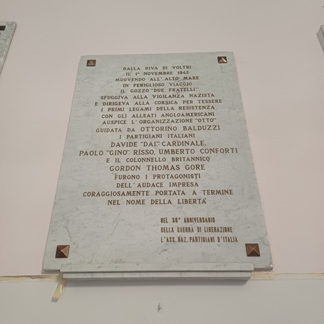 Lapide in marmo con lunga iscrizione, fissata a una parete interna con borchie agli angoli.