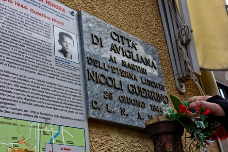 Lapide commemorativa dedicata a Nicoli, simbolo di libertà a Avigliana, con omaggi floreali.