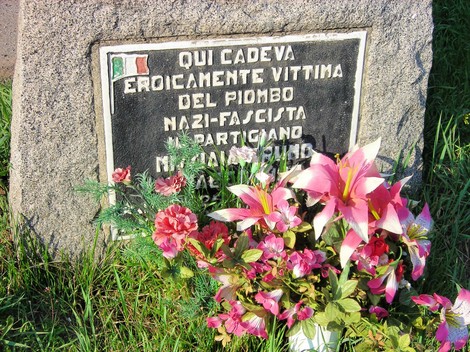 Cippo commemorativo con fiori, in ricordo di un partigiano vittima del regime nazi-fascista.