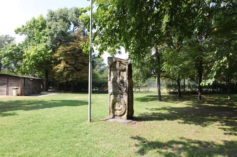 Monumento ai caduti per la libertà, immerso nel verde di un parco con alberi e prato.