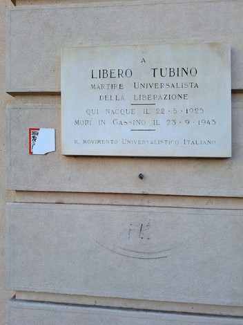 Lapide dedicata a Libero Tubino, martire universalista della liberazione, situata su un muro di pietra.