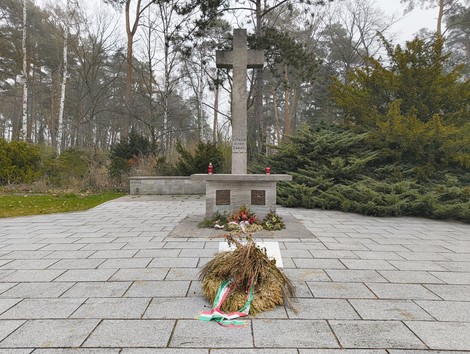 Cimitero militare italiano di Zehlendorf, con un crocifisso, decorazioni floreali e un'atmosfera di calma e rispetto.