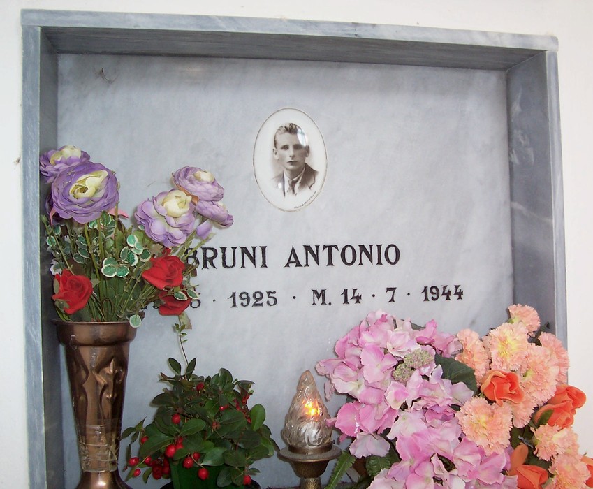 Cappella dei Caduti Partigiani, commemorazione di eroi con fiori e un ritratto.