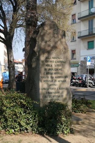 Cippo commemorativo per il decennale della Liberazione, situato in un'area pubblica, circondato da vegetazione.