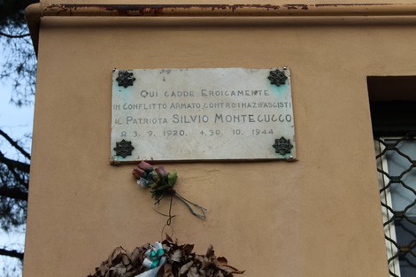Lapide commemorativa a Montecucco in onore del patriota Silvio Montecucco, decorata con fiori e foglie.