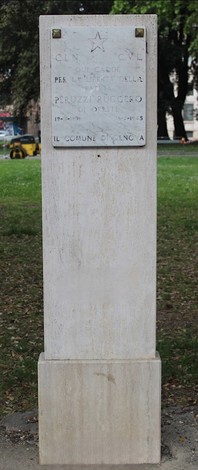 Cippo commemorativo di Peruzzi in un parco, con istruzioni e dedica scolpite su una pietra di colore chiaro.