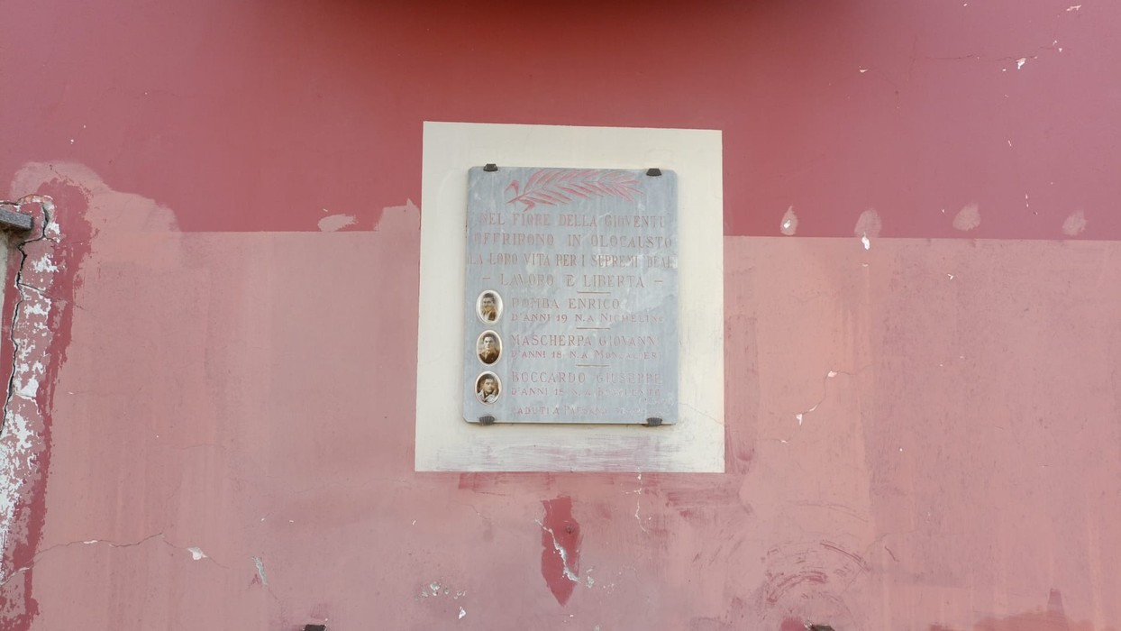 Lapide commemorativa che onora Lapide a Pomba, Mascherpa e Boccardo, affissa su una parete rossa.