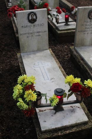 Tombe dedicate ai caduti per la Libertà, adornate con fiori e candele commemorative.