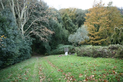 Monumento a Santini immerso nella natura, circondato da alberi e vegetazione, in un'atmosfera tranquilla.