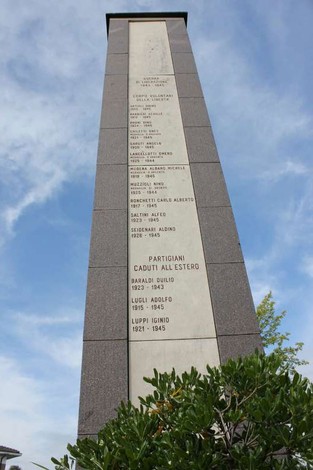 Monumento ai caduti di San Prospero, una stele di pietra con i nomi dei sacrifici e un cielo blu sopra.