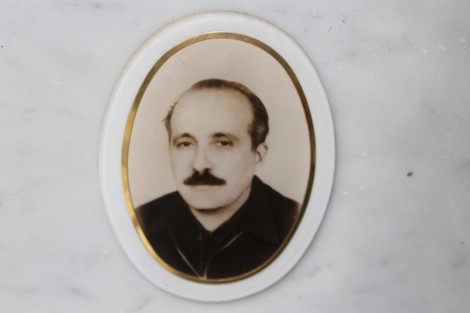 Ritratto di un uomo in bianco e nero, incastonato in un ovale su una superficie marmorea, parte di un memoriale.