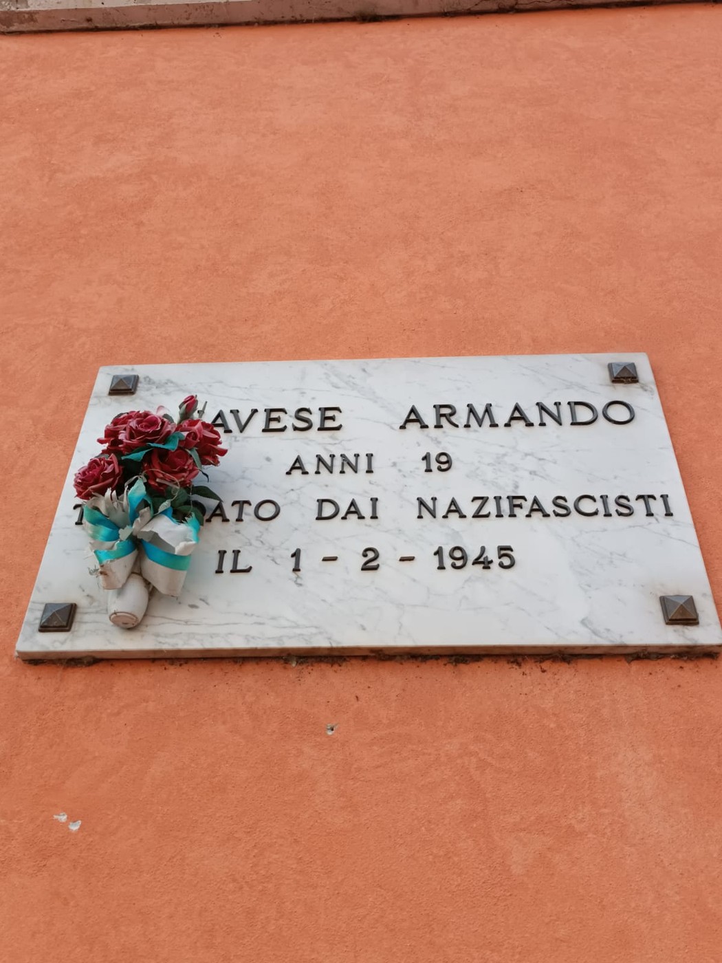 Lapide commemorativa dedicata a Armando Canavese, vittima dei nazifascisti nel 1945. Fiori posti in memoria.