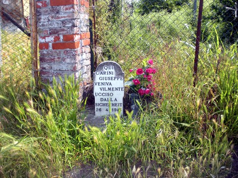 Cippo commemorativo di Giuseppe, ucciso a Carini il 26 aprile 1947, circondato da erba e fiori.