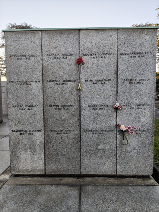 Monumento commemorativo al Campo della Gloria, con lapidi in pietra e fiori freschi.