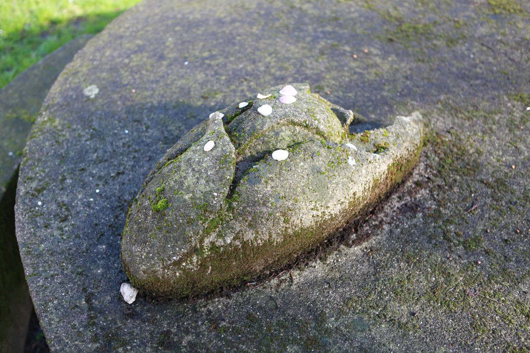 Monumento alla Resistenza con una scultura di pietra, immerso nella natura e decorato da piccoli fiori.