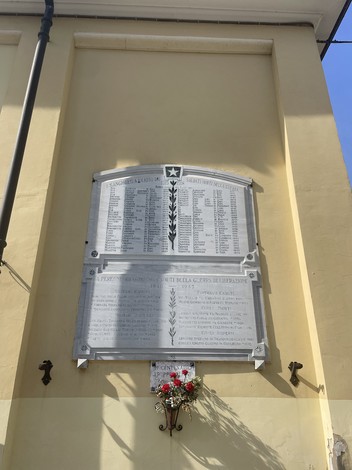 Lapide commemorativa per i caduti della guerra di liberazione, con nomi e date incisi.