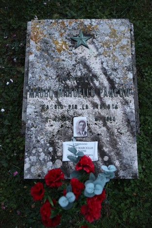 Memoriale per Mauro Marcello Pancon, partigiano, con fiori rossi e una foto commemorativa.