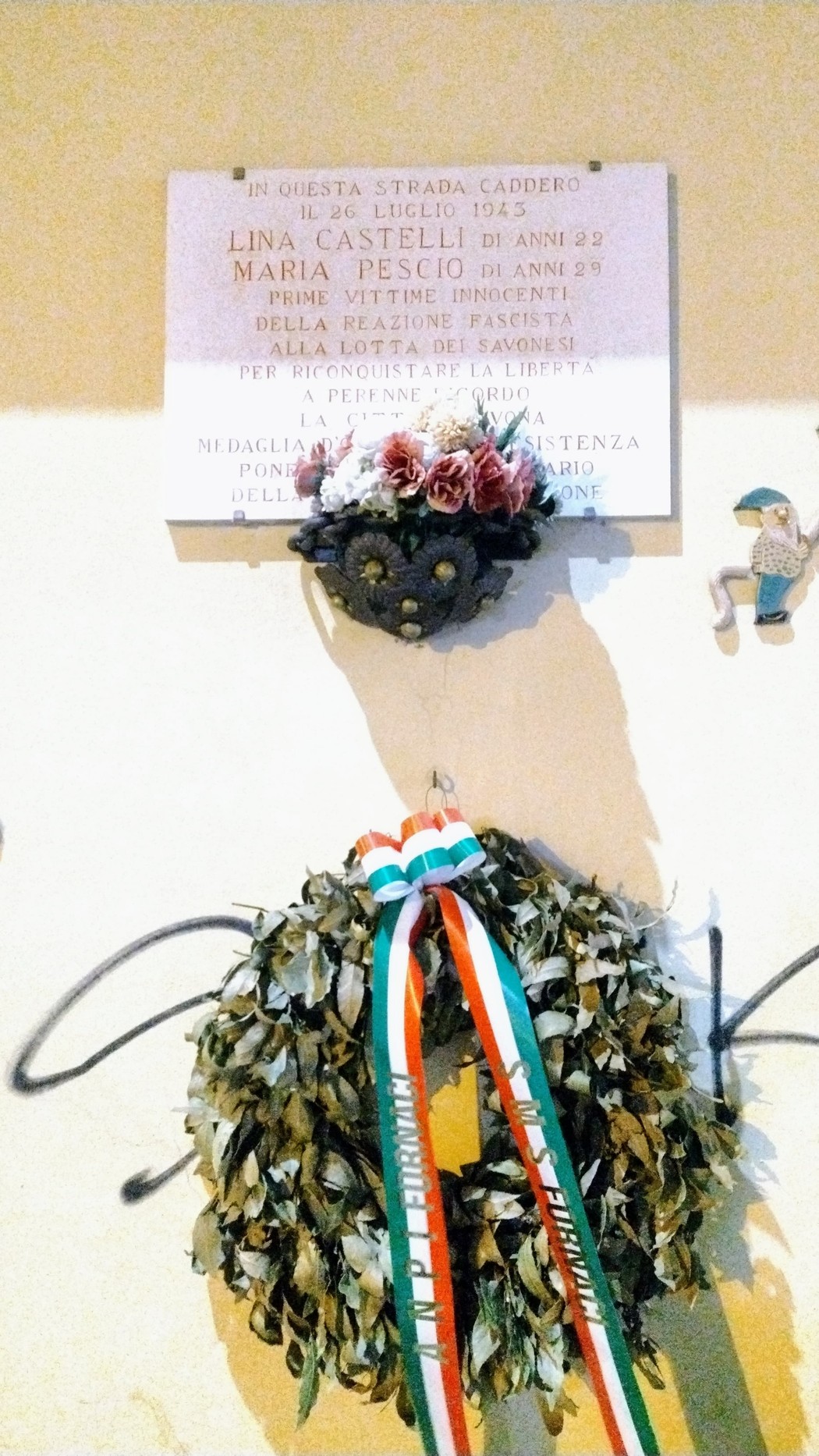 Lapide commemorativa con decorazione floreale, dedicata a Lina Castelli e Maria Pescio.