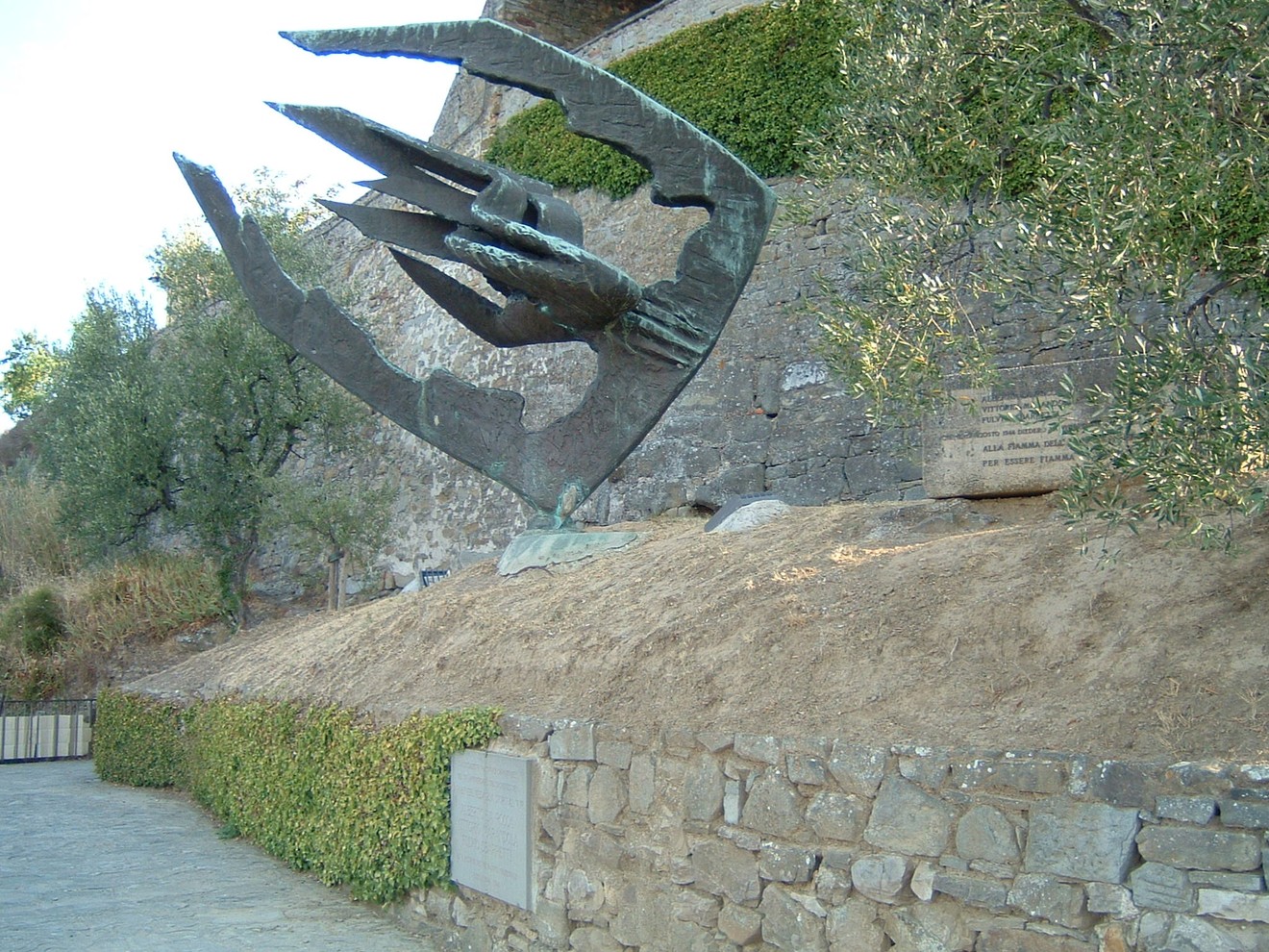 Scultura commemorativa con lapidi in un contesto storico, evidenziando la memoria e la cultura locale.