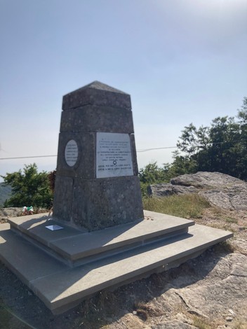 Monumento in Secchieta, struttura in pietra situata su un terreno roccioso, circondata da vegetazione e un cielo sereno.