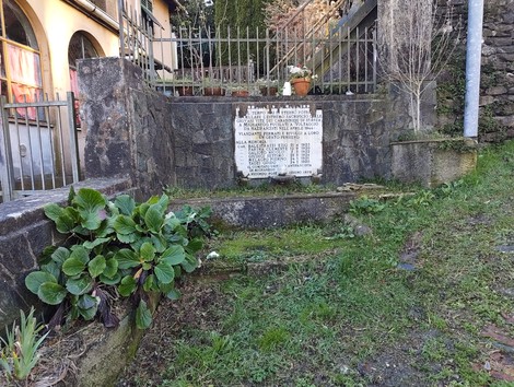 Lapide commemorativa dedicata ai carabinieri di stanza a Mignanego, circondata da piante e vegetazione.