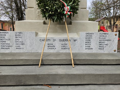 Monumento ai Caduti di Vezzano sul Crostolo con decorazioni floreali e lapidi commemorative.