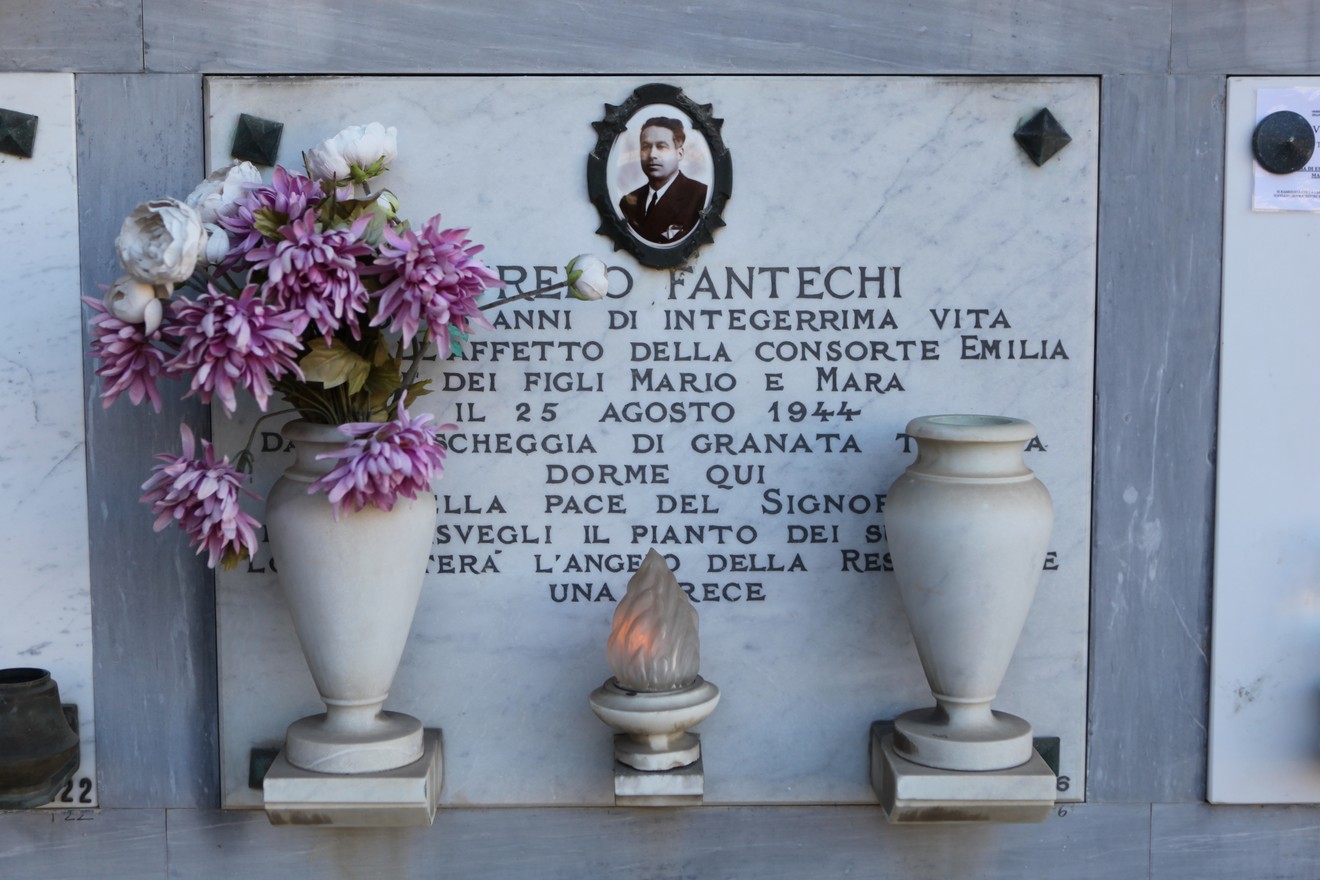 Sepolcro di Fantechi con fiori e luci, commemorazione di una vita dedicata alla famiglia e alla pace.