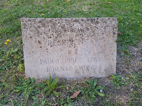 Lastra commemorativa dedicata a Licia e Mugik, situata in un'area verde.