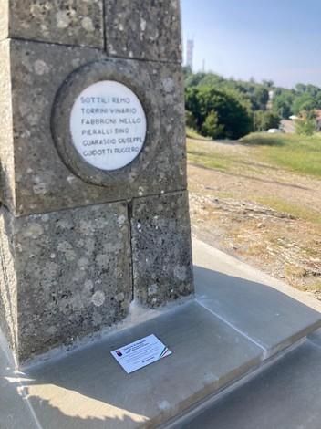 Monumento in Secchieta, con iscrizioni e paesaggio circostante, evidenziando la storia e la cultura locale.