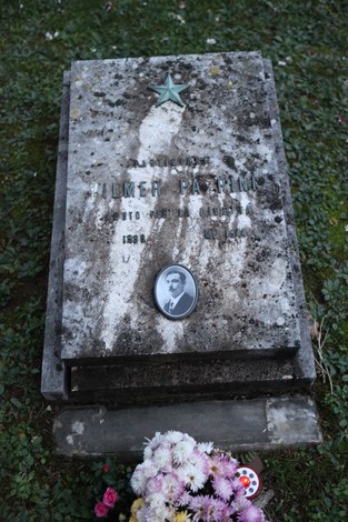 Cippo commemorativo dedicato ai partigiani pratesi, con omaggi floreali e simboli di memoria e resistenza.
