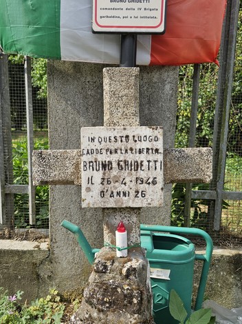 Croce commemorativa di Bruno Ghidetti, in onore della libertà, con dettagli e decorazioni floreali.
